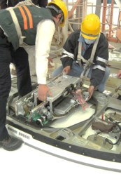 航空機の機体構造部を開放し、複数人で点検・整備作業を行っている様子